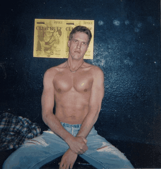a shirtless man sits in front of a club buff flyer