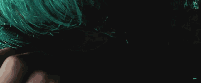 a close up of a person 's face with green hair covering their face
