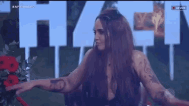 a woman with long hair is standing in front of a sign that says ' a ' on it .