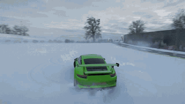 a green car is driving through the snow on a road