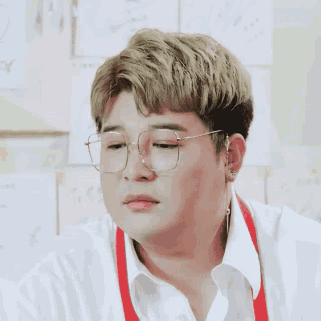 a man wearing glasses and a red apron looks down