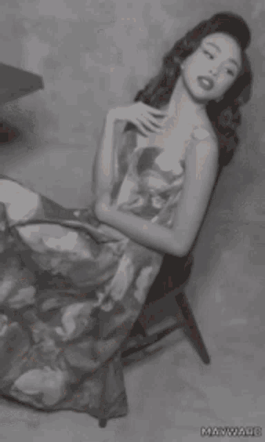 a woman in a floral dress is sitting on a chair with her face painted white