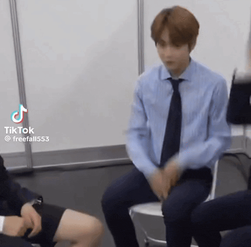 a man in a blue shirt and tie is sitting on a chair in a room .