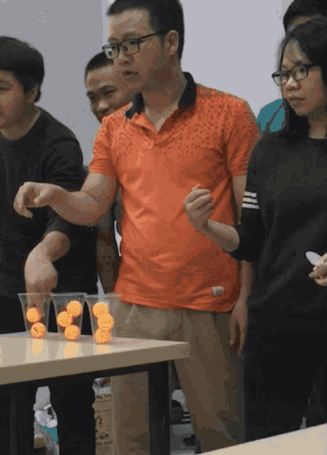 a group of people playing a game with ping pong balls in plastic cups