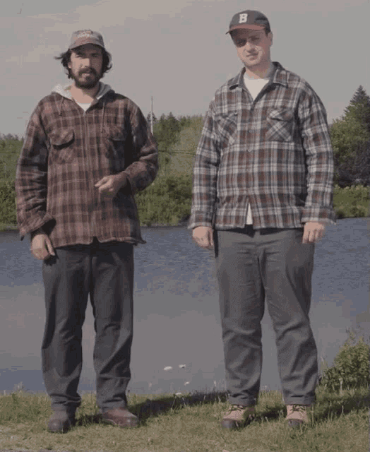 a man wearing a hat with the letter b on it is standing next to another man