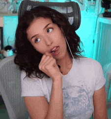 a woman is sitting in a chair with her hand in her mouth