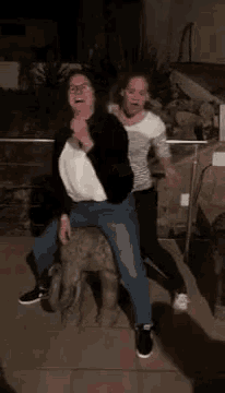 two women are standing next to each other and one of them is sitting on the back of another woman .