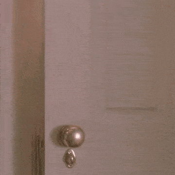 a young boy is peeking out of a door in a home alone movie .