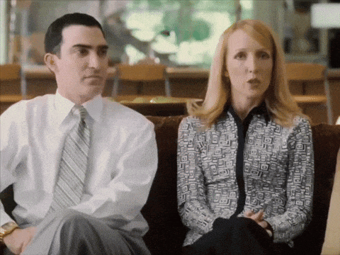 a man and a woman are sitting on a couch and the man is wearing a white shirt and tie