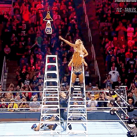 a woman is standing on a ladder in a wrestling ring while a crowd watches