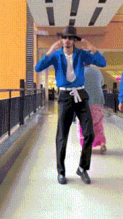 a man in a blue jacket is dancing in a hallway