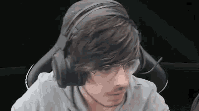 a man wearing headphones and glasses is sitting in a chair in front of a computer .