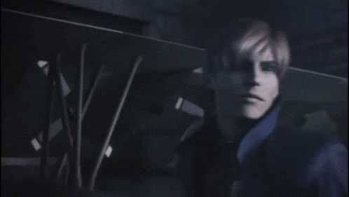 a man in a yellow shirt and a blue jacket is standing in a dark room