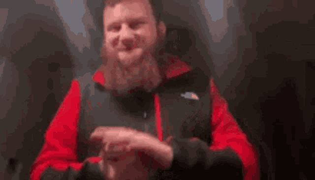 a man with a beard is giving a thumbs up sign while holding a steering wheel .