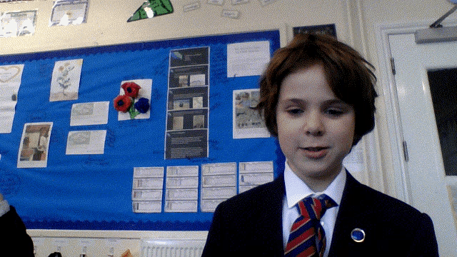a young boy in a suit and tie stands in front of a blue board