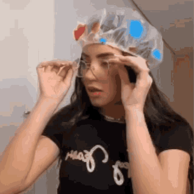 a woman wearing a shower cap and glasses is adjusting her glasses .