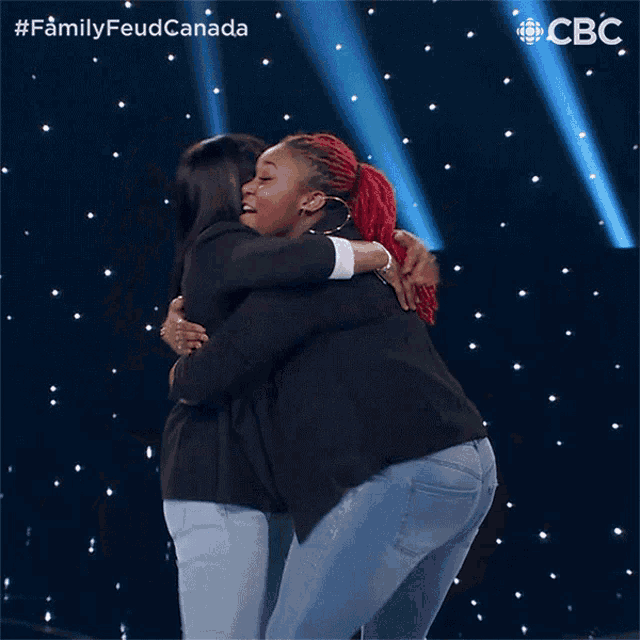 two women hugging each other in front of a cbc logo