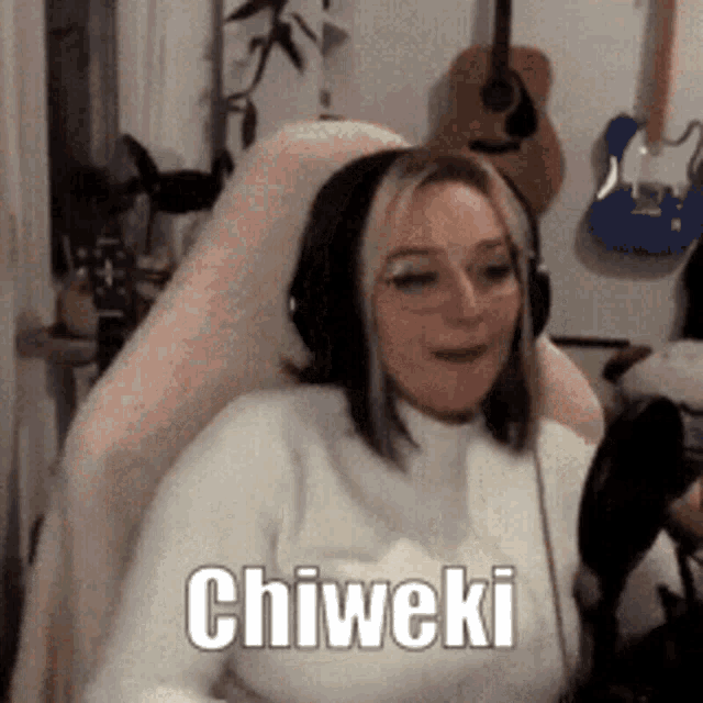 a woman wearing headphones is sitting in a chair with the word chiweki on her chest