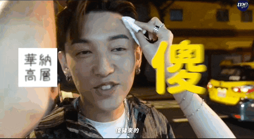 a man wipes his forehead with a napkin in front of a blue sign that says mc