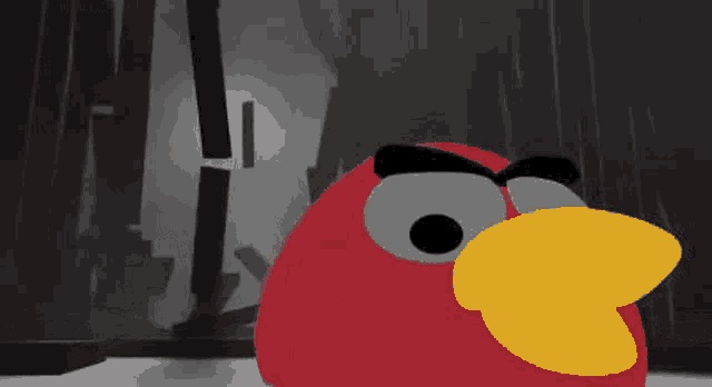 a red angry bird with a yellow beak is standing in front of a dark background .