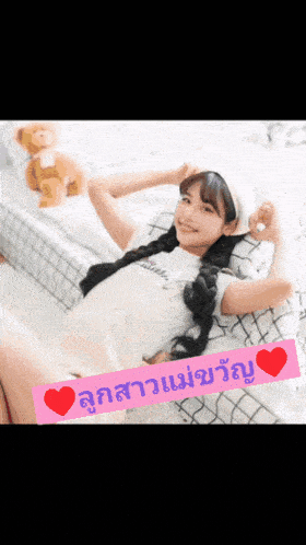 a girl is laying on a bed with a teddy bear and a sign that says ' i love you '