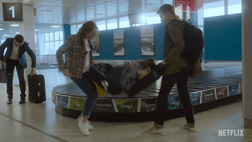 a group of people standing around a luggage belt that says netflix on the bottom