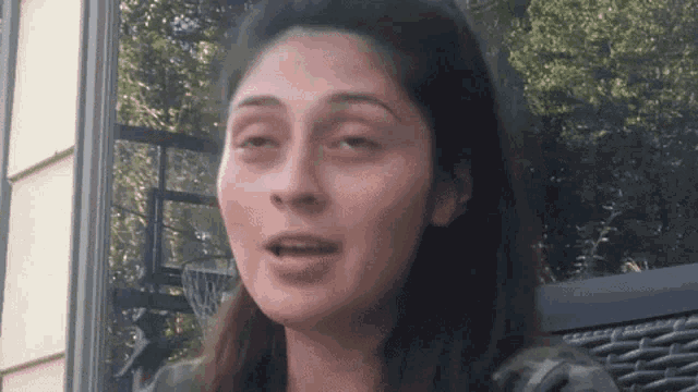 a close up of a woman 's face with a basketball hoop behind her