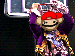 a monkey wearing a red hat and purple coat
