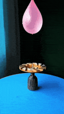 a pink balloon is floating over a drill bit on a blue table