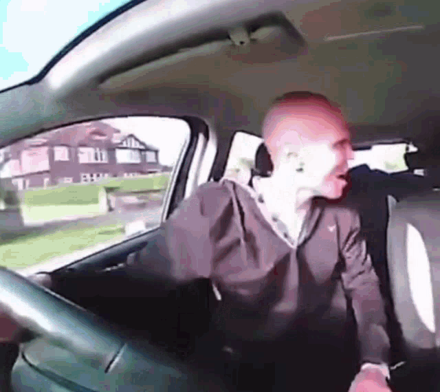 a man is sitting in the driver 's seat of a car .