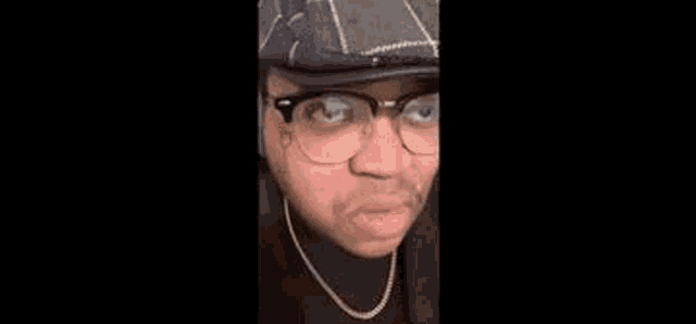 a man wearing glasses and a hoodie is making a face .