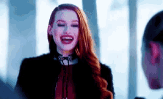 a woman with red hair is laughing while standing next to a window .