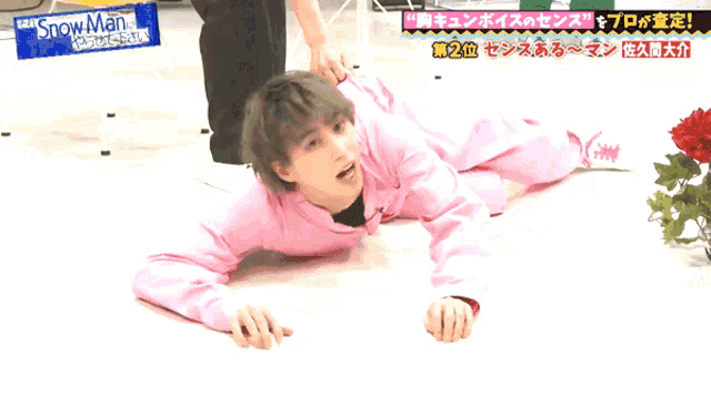 a man in a pink shirt is crawling on the floor with a sign that says snow man
