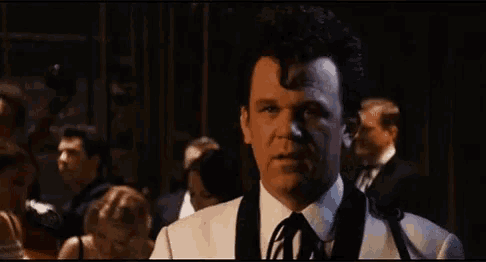a man in a tuxedo and tie is standing in front of a crowd and asking how are we supposed to follow that ?