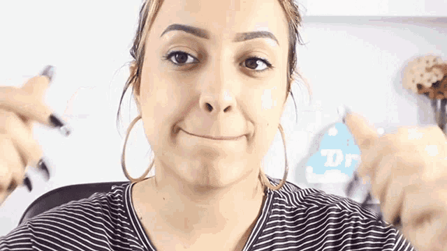 a woman wearing hoop earrings is making a funny face and holding a pen
