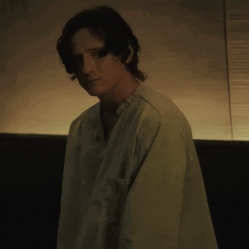 a man in a green shirt is standing in the dark