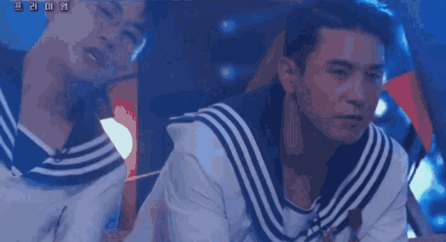 a man wearing a sailor 's uniform is sitting on a stage