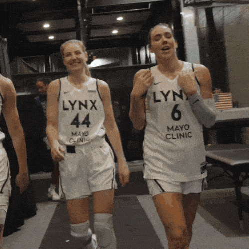 two female lynx basketball players wearing white jerseys
