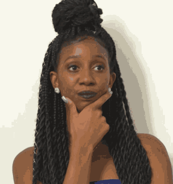 a woman with braids has her hand to her chin
