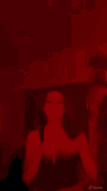 a woman is covering her mouth with her hands in a red light .