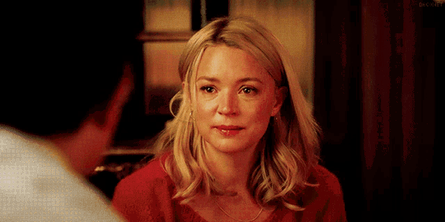 a woman in a red sweater is looking at a man in a white shirt