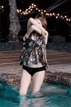 a woman in a bathing suit is standing in a pool .