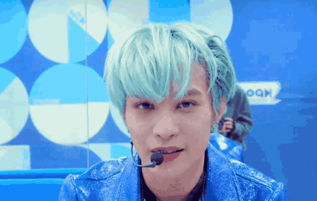 a man with green hair is wearing a blue jacket