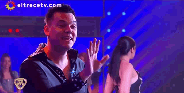 a man and a woman singing on a stage with eltrecetv.com on the bottom