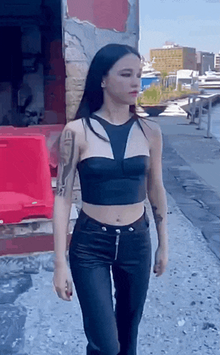 the woman is wearing a black crop top and black leather pants .
