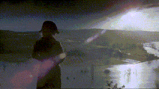 a man in a black hat stands in front of a river