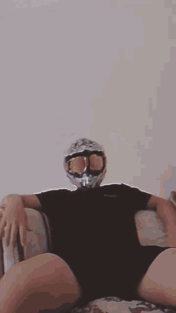 a person wearing a helmet and goggles is laying on a couch .