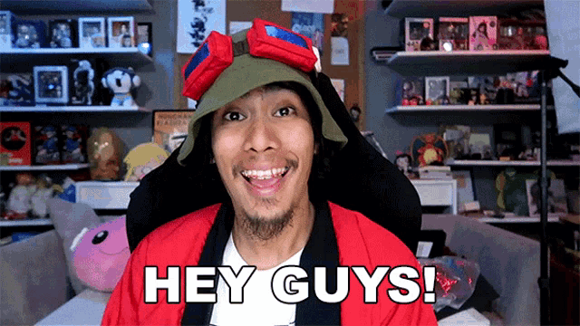 a man wearing a red jacket and a hat says hey guys