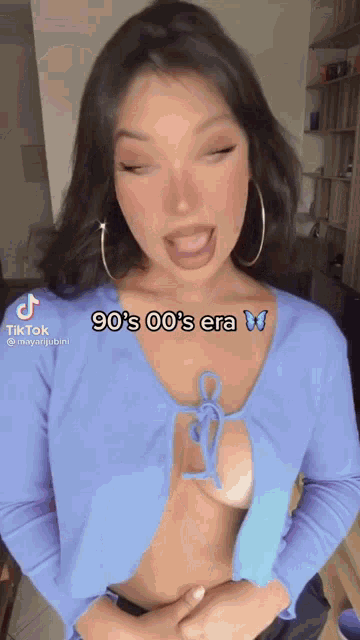 a woman is wearing a blue shirt with a plunging neckline and a blue butterfly on her chest .