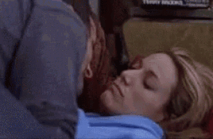 a woman in a blue hoodie is laying on a couch .